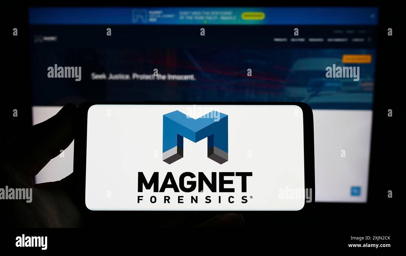 Stuttgart, Allemagne, 01-30-2023, personne tenant un smartphone avec le logo de la société de cybersécurité Magnet Forensics Inc. sur l'écran devant le site Web. Banque D'Images