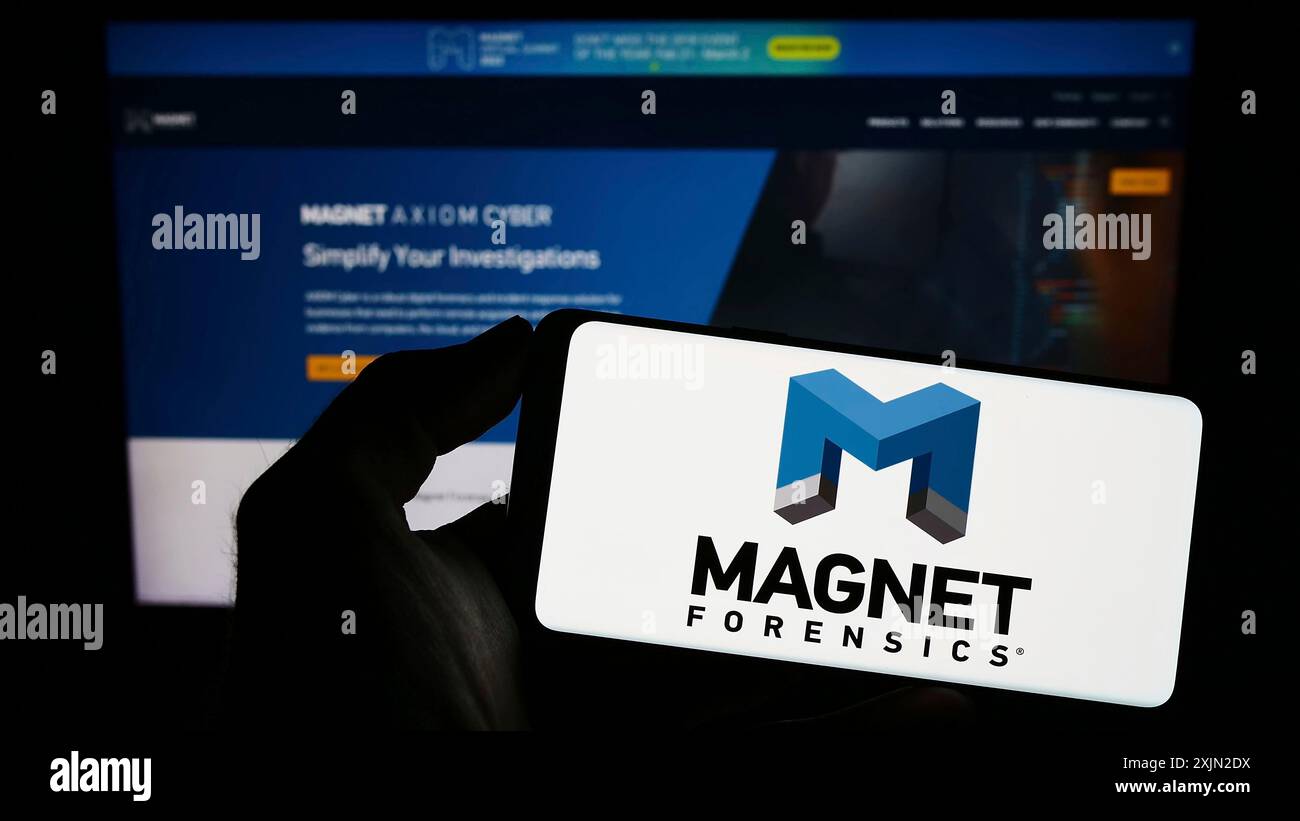 Stuttgart, Allemagne, 01-30-2023, personne tenant un téléphone portable avec le logo de la société de cybersécurité Magnet Forensics Inc. sur l'écran devant la page Web. Banque D'Images