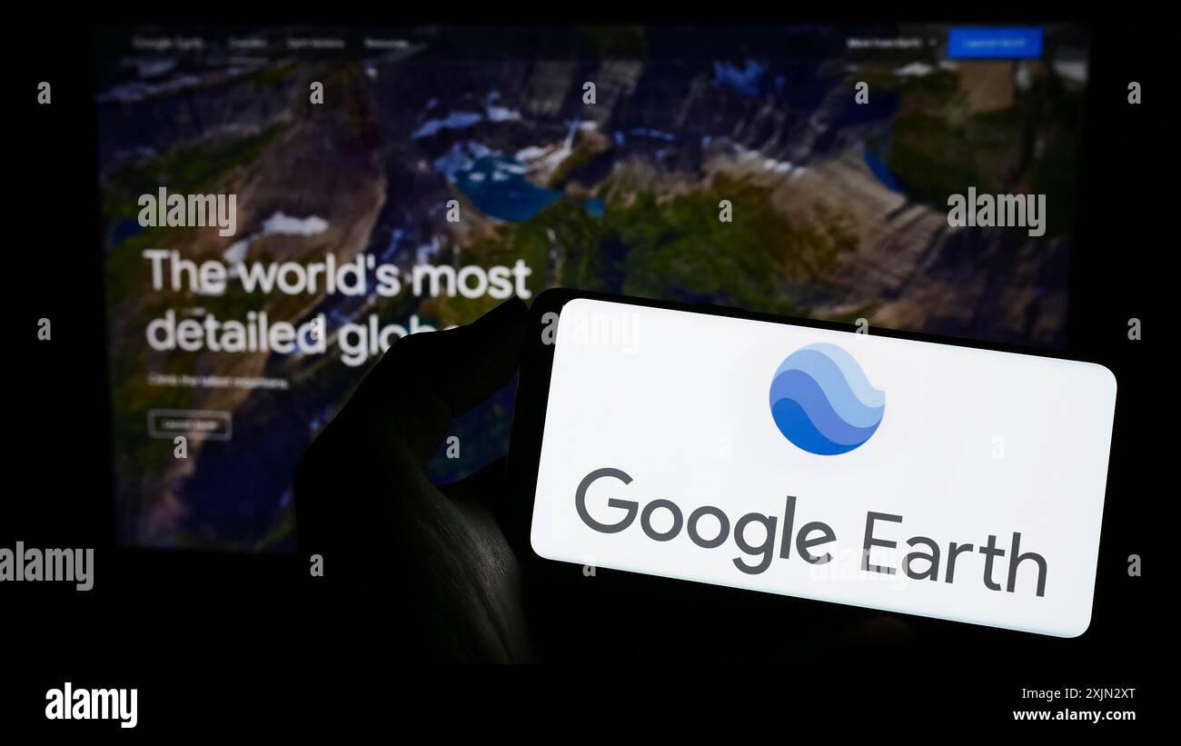 Stuttgart, Allemagne, 03-10-2023 : personne tenant un téléphone portable avec le logo du logiciel d'imagerie satellite Google Earth sur l'écran en face de la page Web. Banque D'Images