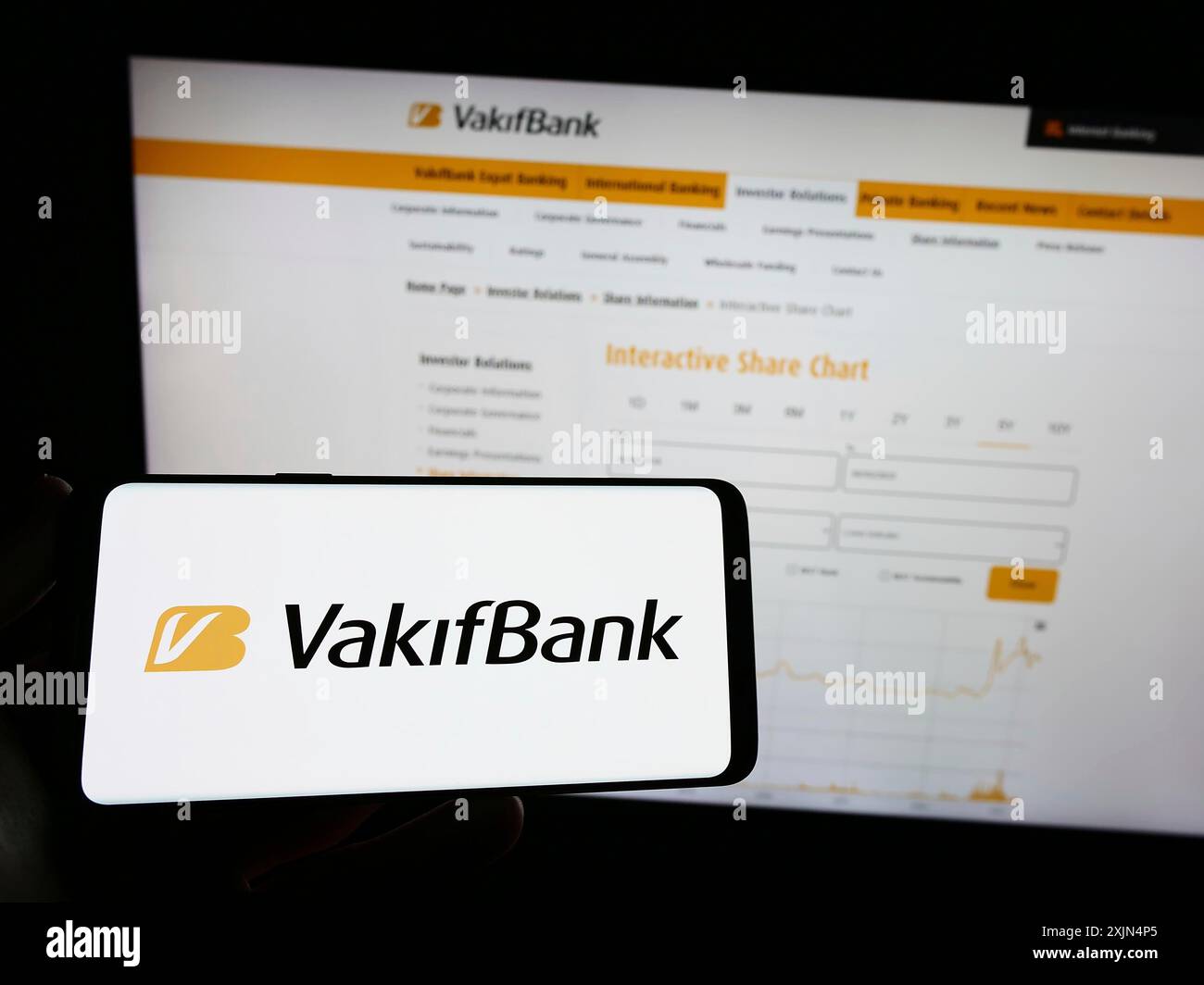 Stuttgart, Allemagne, 04-02-2023 : personne tenant un téléphone portable avec le logo de Turkiye Vakiflar Bankasi T.A.O. (Vakifbank) sur l'écran devant la page web. Banque D'Images