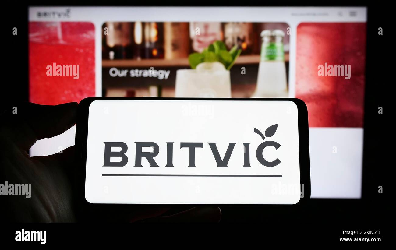 Stuttgart, Allemagne, 04-02-2023 : personne tenant un smartphone avec le logo de la société britannique de boissons gazeuses Britvic plc sur l'écran devant le site Web. Mise au point Banque D'Images