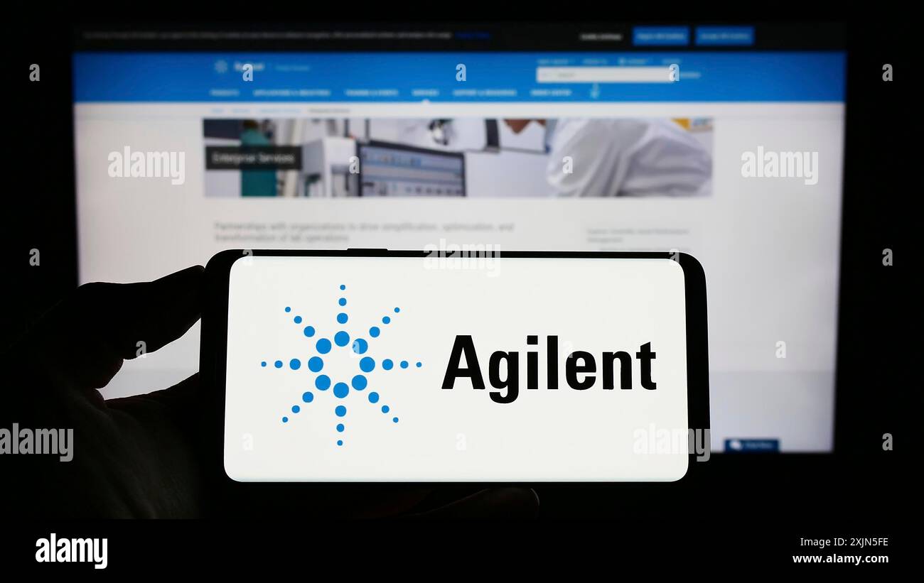 Stuttgart, Allemagne, 04-26-2023, personne tenant un téléphone portable avec le logo de la société américaine Agilent technologies Inc. sur l'écran devant la page Web de l'entreprise. Banque D'Images