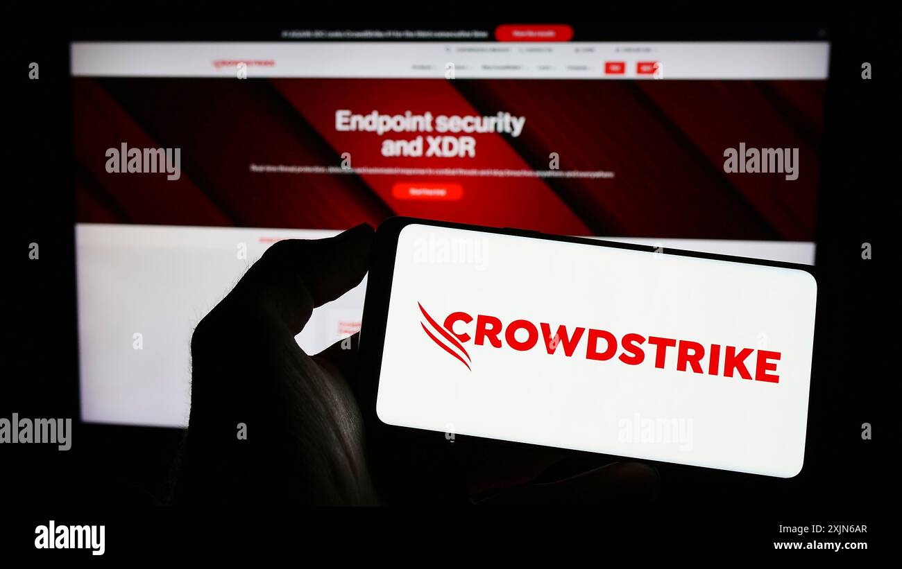 Stuttgart, Allemagne, 03-31-2023, personne tenant un smartphone avec le logo de la société de cybersécurité CrowdStrike Holdings Inc. sur l'écran devant le site Web. Banque D'Images