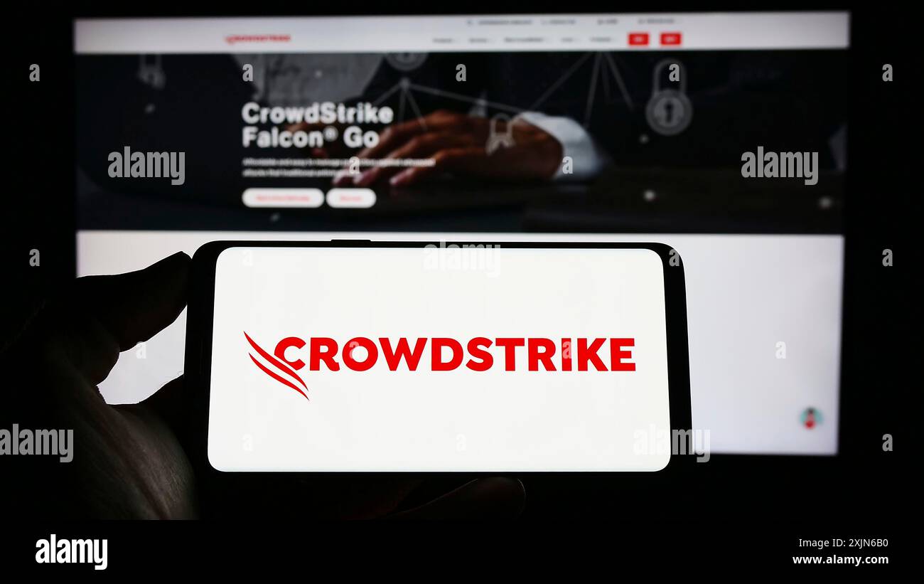 Stuttgart, Allemagne, 03-31-2023, personne tenant un téléphone portable avec le logo de la société de cybersécurité CrowdStrike Holdings Inc. sur l'écran devant la page web. Banque D'Images