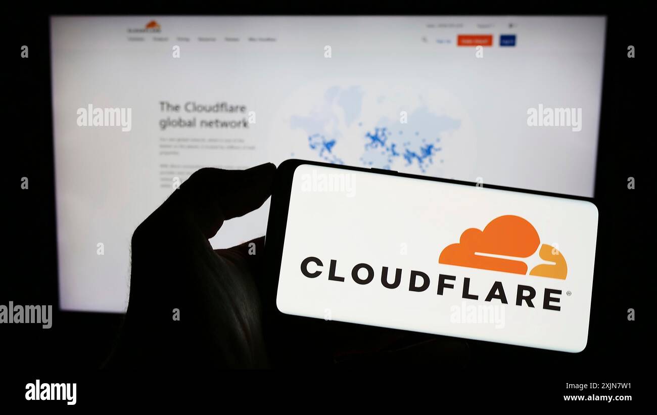 Stuttgart, Allemagne, 06-17-2023 : personne tenant un smartphone avec le logo de la société américaine de TIC Cloudflare Inc sur l'écran devant le site Web. Concentrez-vous sur le téléphone Banque D'Images