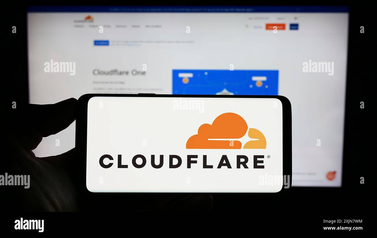 Stuttgart, Allemagne, 06-17-2023 : personne tenant un téléphone portable avec le logo de la société américaine de TIC Cloudflare Inc sur l'écran en face de la page Web de l'entreprise. Concentrez-vous sur Banque D'Images