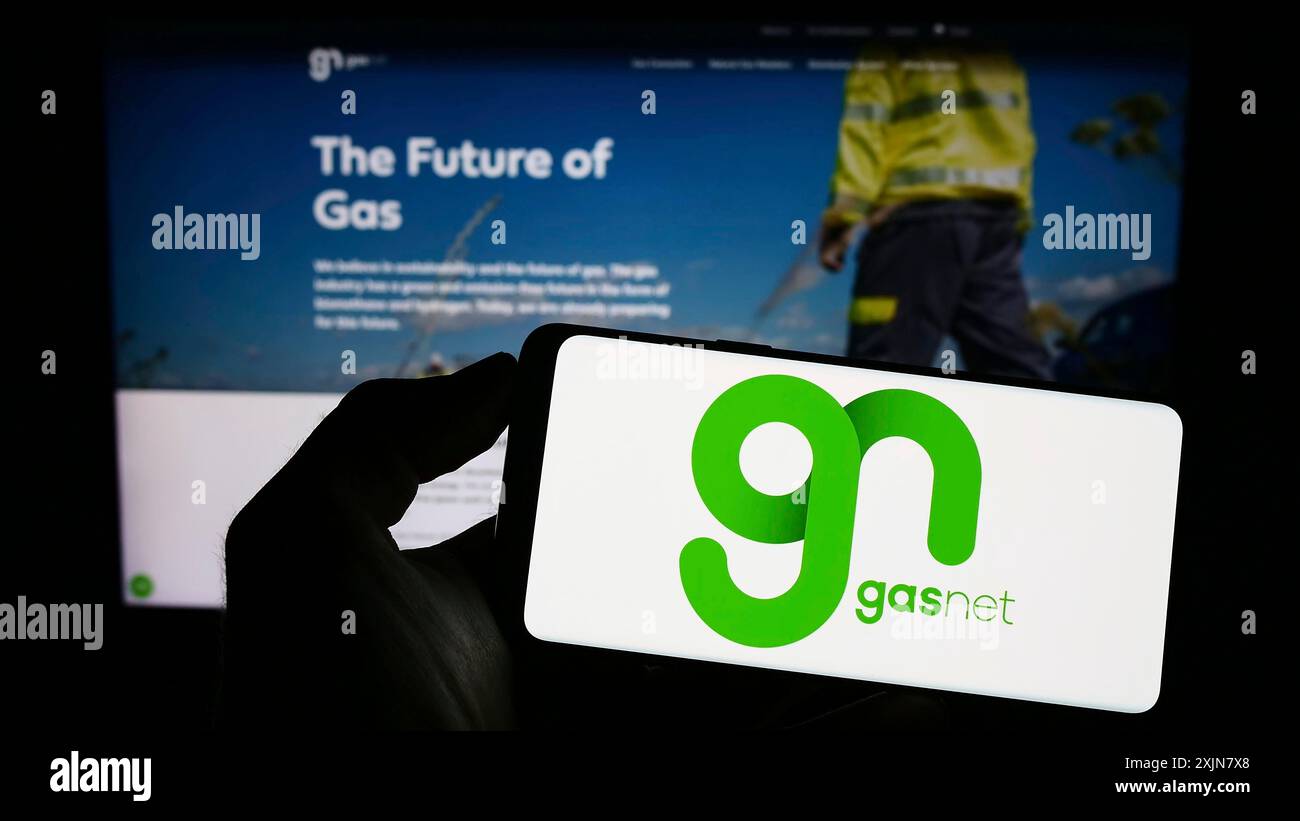 Stuttgart, Allemagne, 06-18-2023 : personne tenant un téléphone portable avec le logo de la société tchèque de distribution de gaz GasNet sro sur l'écran devant l'entreprise Banque D'Images