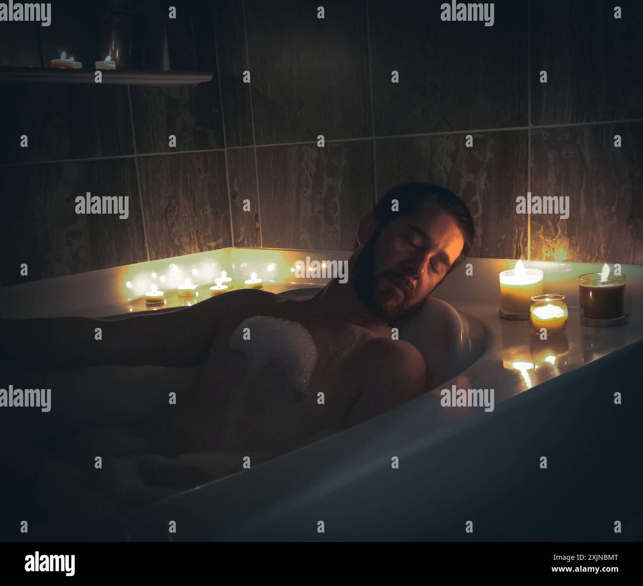 Candlelit Serenity : homme nu dans Bubble Bath Boudoir Banque D'Images