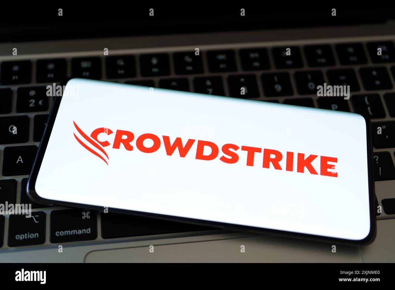 Logo CrowdStrike vu sur l'écran du smartphone pled sur l'ordinateur portable. Entreprise de cybersécurité derrière la panne INFORMATIQUE mondiale. Stafford, Royaume-Uni, 19 juillet Banque D'Images