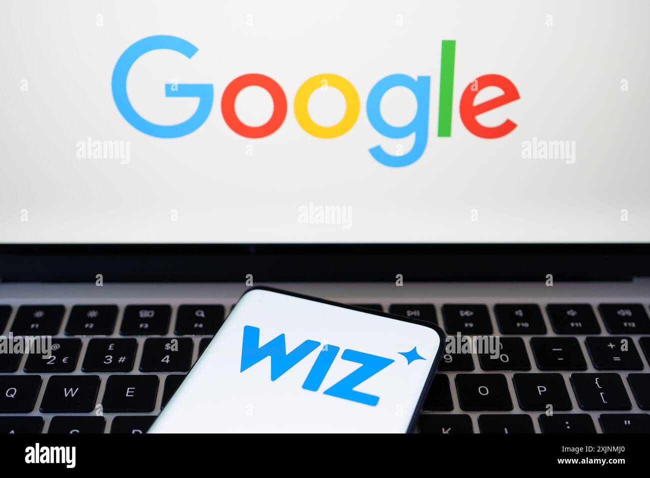 Logos Wiz et Google visibles sur les écrans des smartphones et des ordinateurs portables. Concept de reprise d'entreprise. Stafford, Royaume-Uni, 17 juillet 2024 Banque D'Images