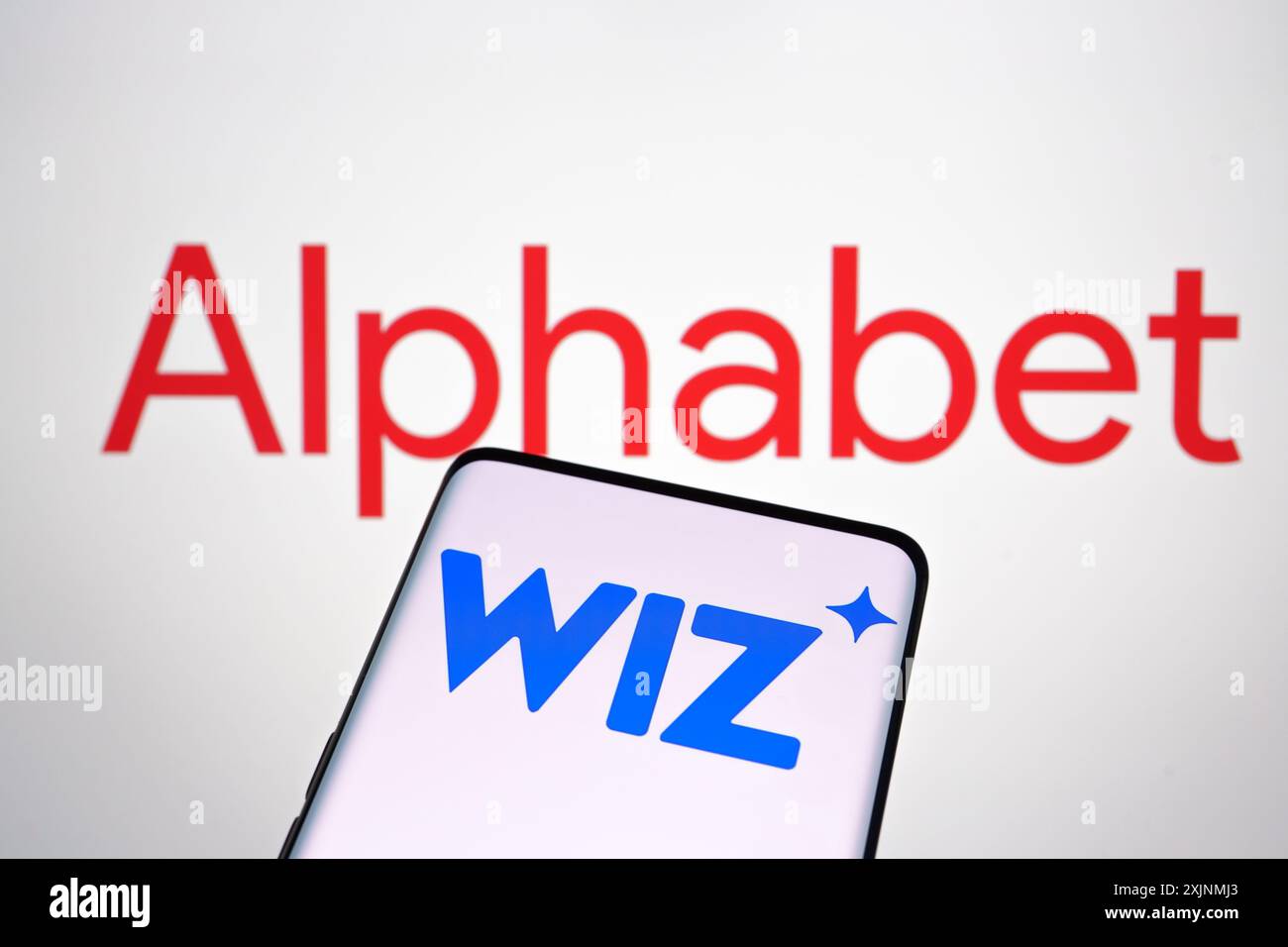 Logos de la société Wiz et Alphabet visibles sur les écrans des smartphones et des ordinateurs portables. Concept de reprise d'entreprise. Stafford, Royaume-Uni, 17 juillet 2024 Banque D'Images