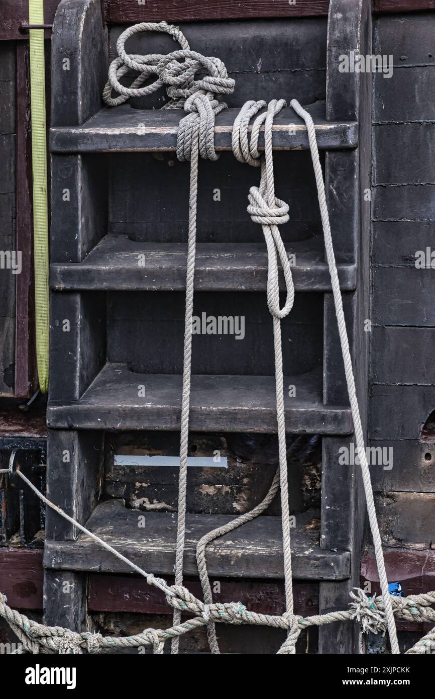 Gros plan d'une échelle en bois altérée avec des cordes attachées autour, sur un bateau. Banque D'Images