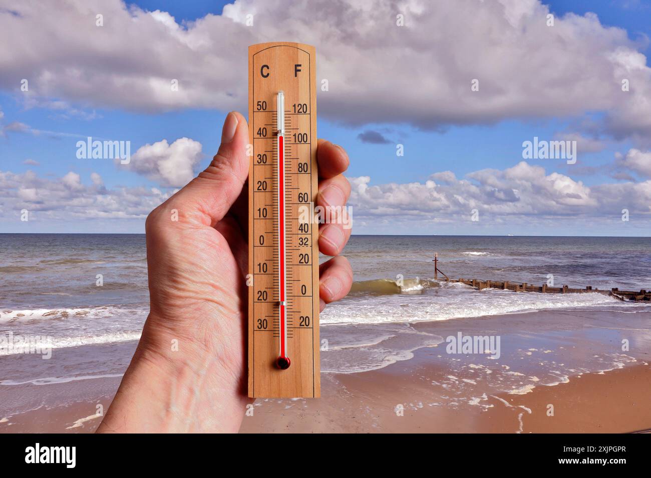Image conceptuelle d'une personne tenant un thermomètre pour représenter la hausse des températures de la mer. Banque D'Images