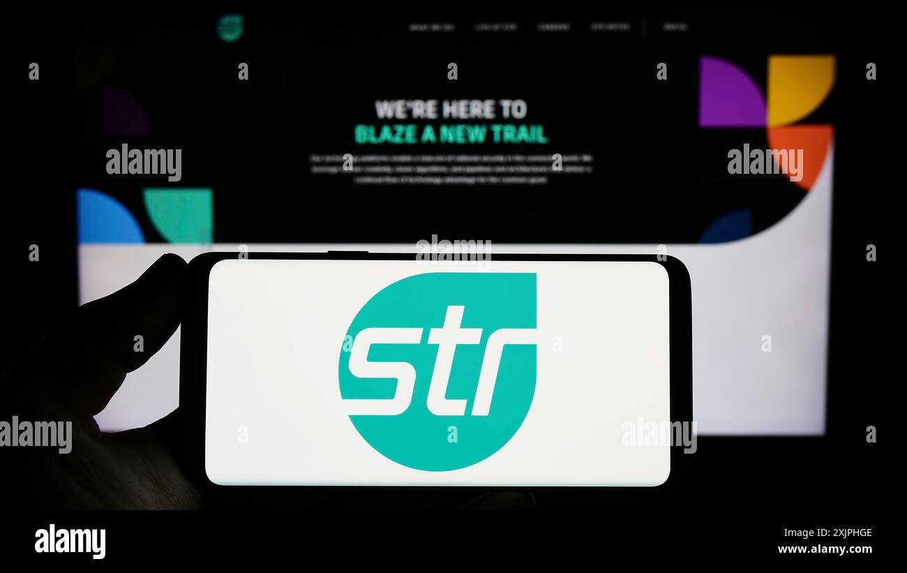 Stuttgart, Allemagne, 06-18-2023 : personne tenant un smartphone avec le logo de Systems and Technology Research LLC (STR) sur l'écran devant le site Web. Mise au point Banque D'Images