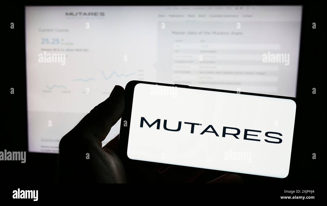 Stuttgart, Allemagne, 06-24-2023 : personne tenant un téléphone portable avec le logo de la société d'investissement allemande Mutares se Co. KGaA sur l'écran devant le web Banque D'Images