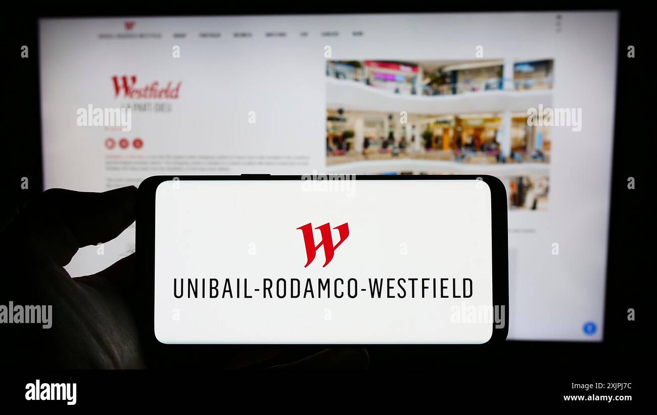 Stuttgart, Allemagne, 07-01-2023 : personne tenant un téléphone portable avec le logo de la société immobilière Unibail-Rodamco-Westfield se sur l'écran en face de la page web. Banque D'Images