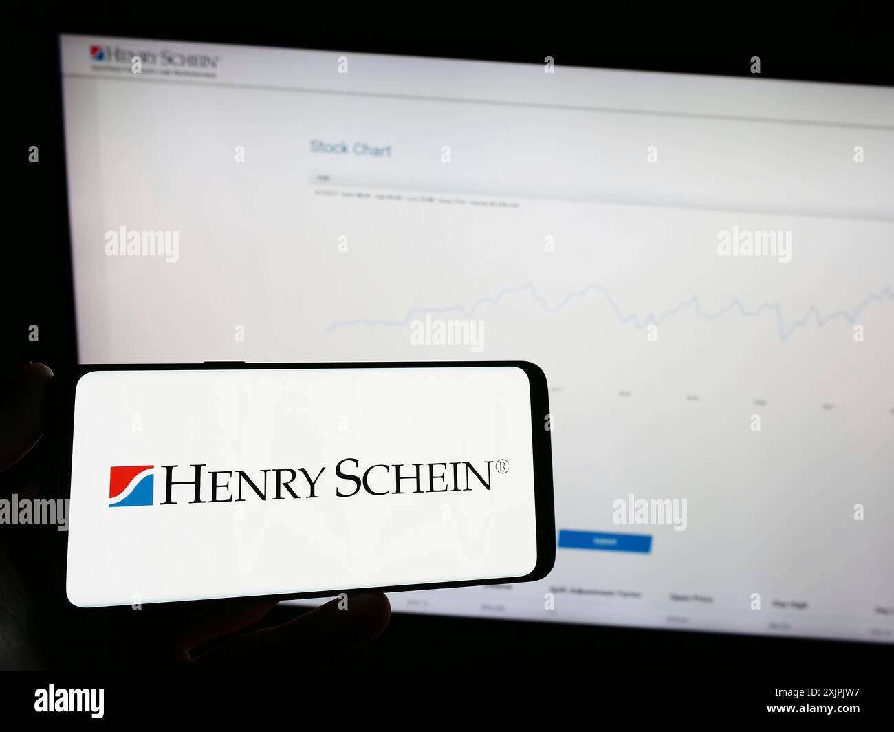 Stuttgart, Allemagne, 07-02-2023 : personne tenant un téléphone portable avec le logo de la société américaine de produits de santé Henry Schein Inc sur l'écran devant le web Banque D'Images
