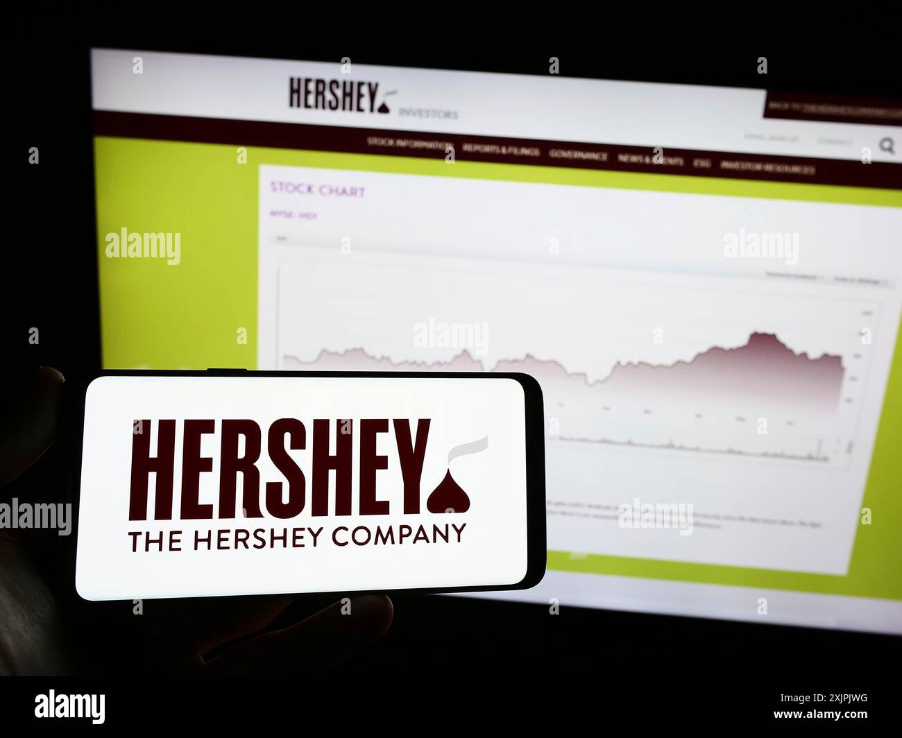 Stuttgart, Allemagne, 07-02-2023 : personne tenant un téléphone portable avec le logo de l'entreprise alimentaire américaine The Hershey Company sur l'écran en face de la page Web. Banque D'Images