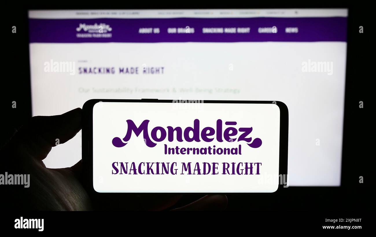 Stuttgart, Allemagne, 08-05-2023 : personne tenant un téléphone portable avec le logo de la société alimentaire américaine Mondelez International Inc sur l'écran devant l'entreprise Banque D'Images