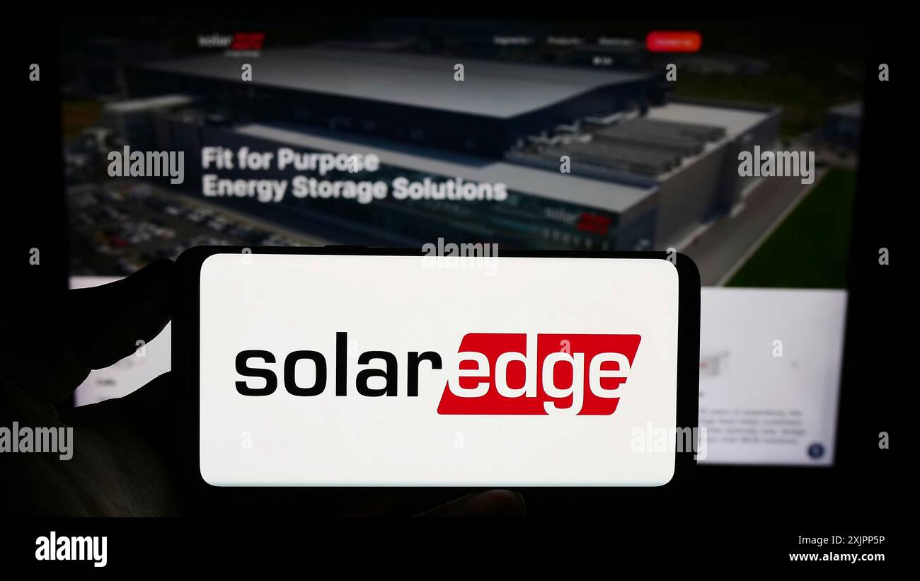 Stuttgart, Allemagne, 08-08-2023 : personne tenant un smartphone avec le logo de la société israélienne SolarEdge technologies Inc sur l'écran devant le site. Banque D'Images