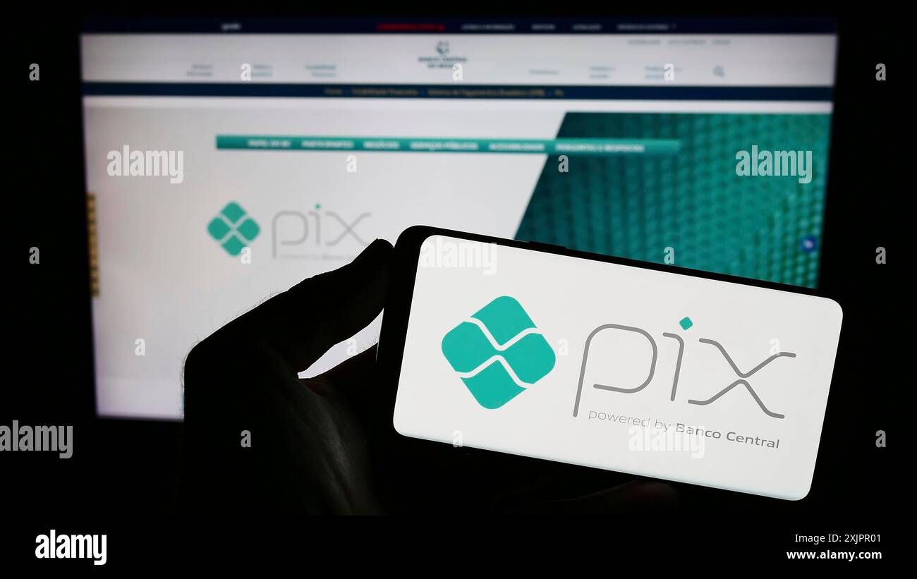 Stuttgart, Allemagne, 08-17-08 2023 : personne tenant un smartphone avec le logo de la plate-forme brésilienne de paiement instantané Pix sur l'écran devant le site Web. Concentrez-vous sur Banque D'Images