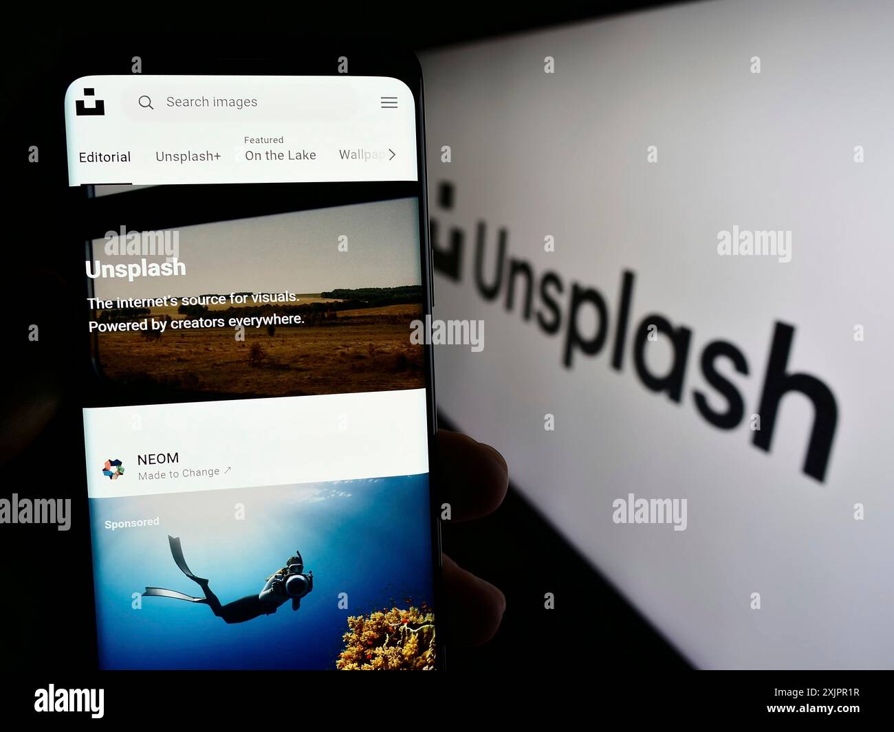 Stuttgart, Allemagne, 08-18-2023 : personne tenant un smartphone avec la page web de la société de photographie Unsplash Inc. sur l'écran devant le logo. Mise au point Banque D'Images