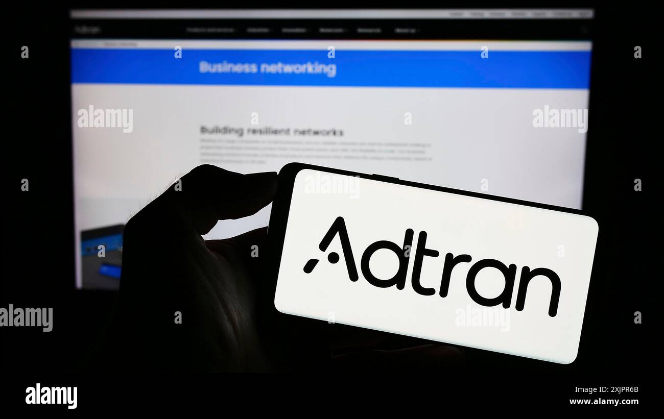 Stuttgart, Allemagne, 08-20-2023 : personne tenant un téléphone portable avec le logo de la société de télécommunications américaine Adtran Inc sur l'écran devant l'entreprise Banque D'Images