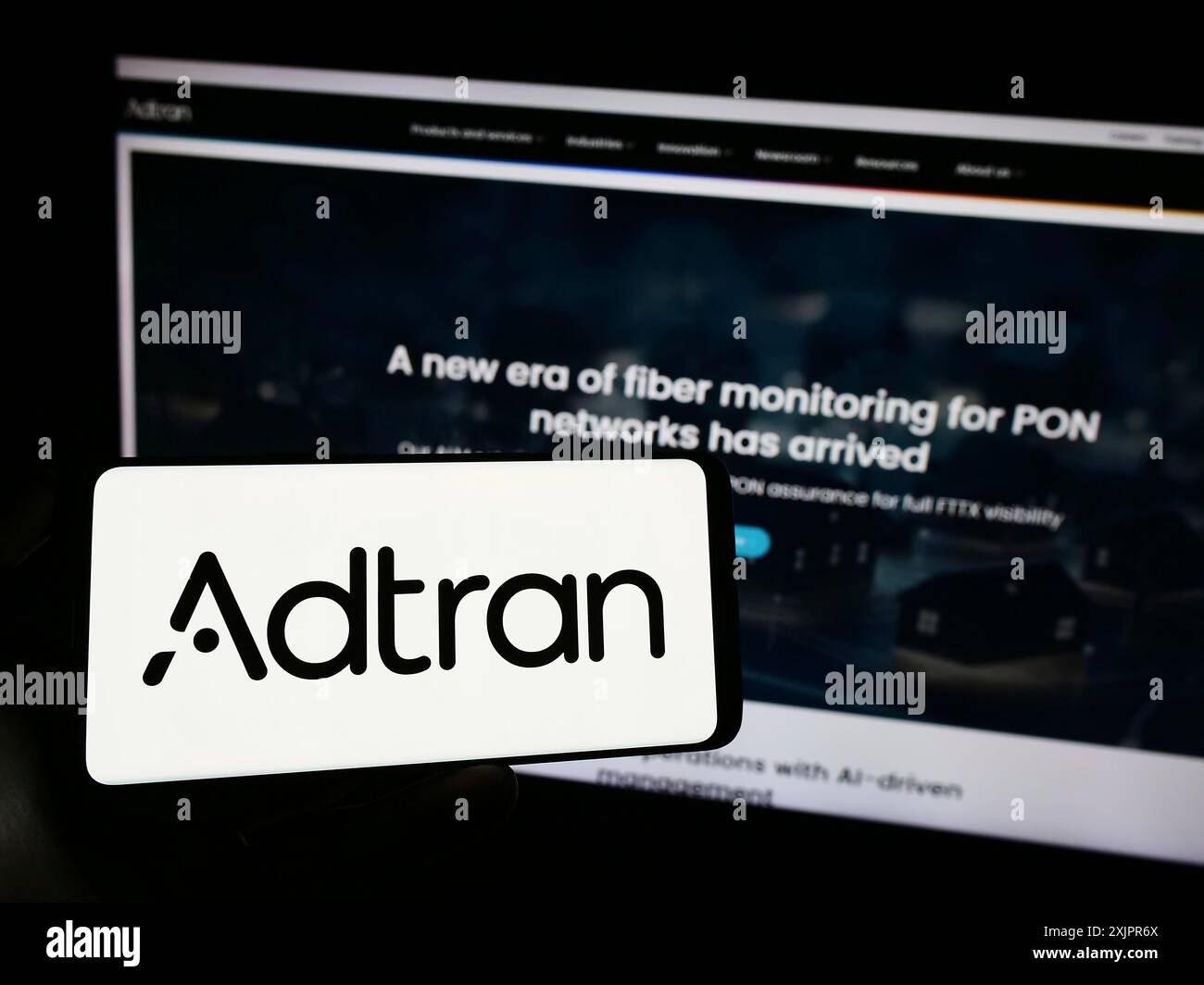 Stuttgart, Allemagne, 08-20-08 2023 : personne tenant un smartphone avec le logo de la société de télécommunications américaine Adtran Inc sur l'écran devant le site Web. Mise au point Banque D'Images