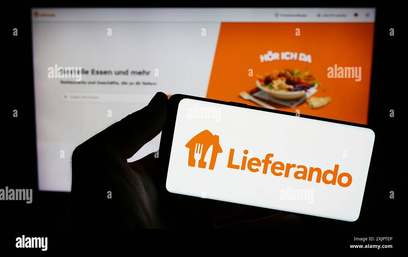 Stuttgart, Allemagne, 09-10-2023 : personne tenant un smartphone avec le logo de la société allemande de livraison de nourriture Lieferando sur l'écran devant le site Web. Mise au point Banque D'Images