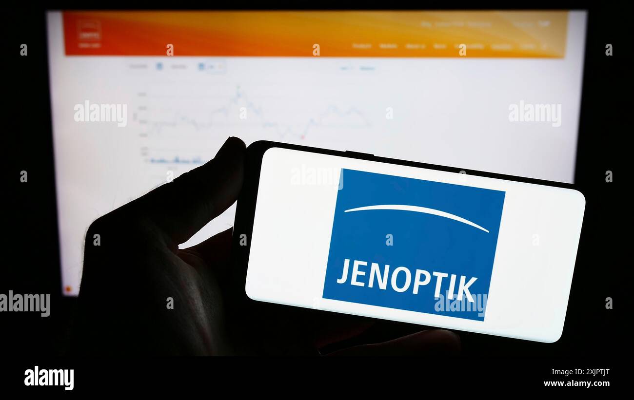 Stuttgart, Allemagne, 09-10-2023 : personne tenant un téléphone portable avec le logo de la société de photonique allemande Jenoptik AG sur l'écran devant le web d'affaires Banque D'Images