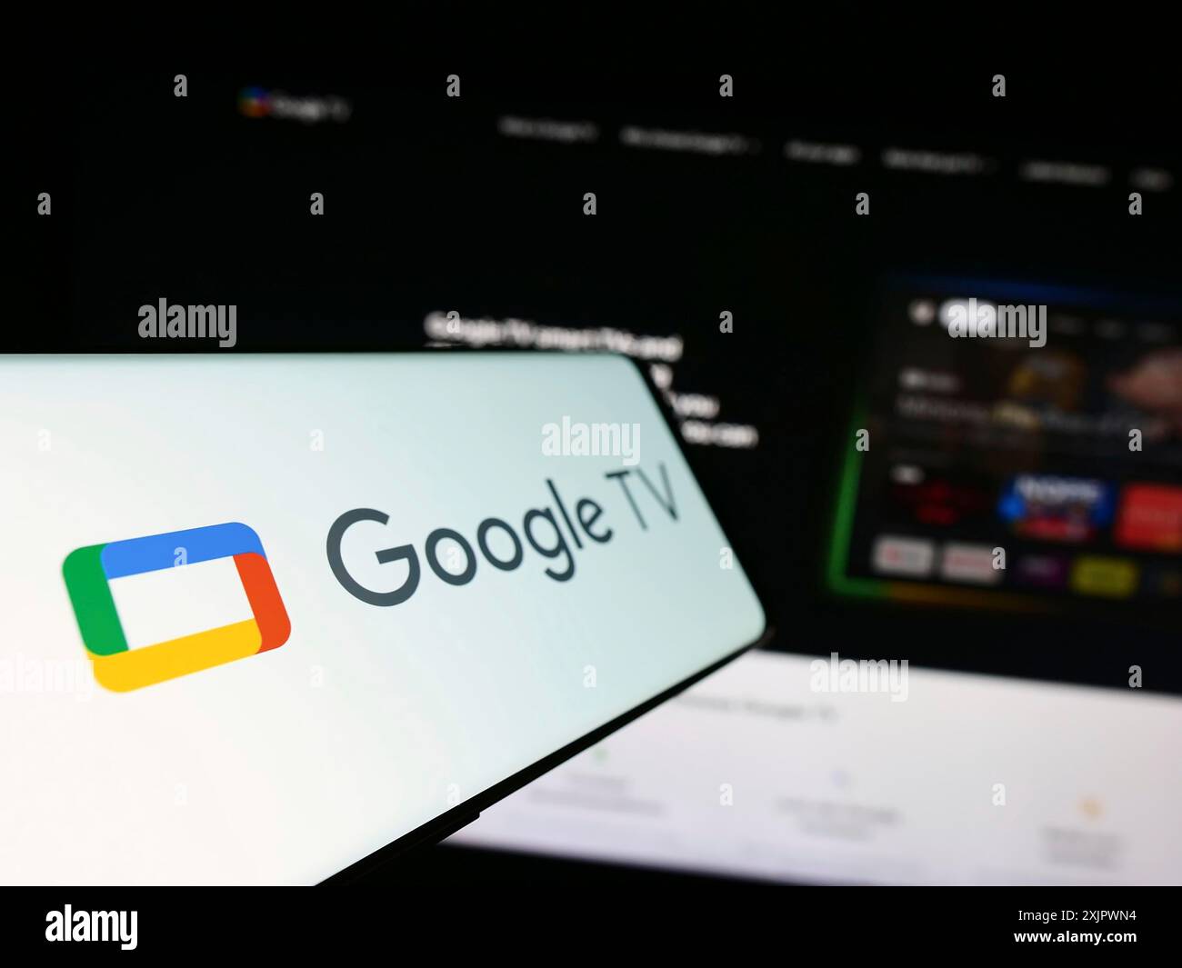 Stuttgart, Allemagne, 09-23-2023 : smartphone avec logo de service de vidéo à la demande Google TV sur l'écran en face du site Web de l'entreprise. Focus à gauche de Banque D'Images
