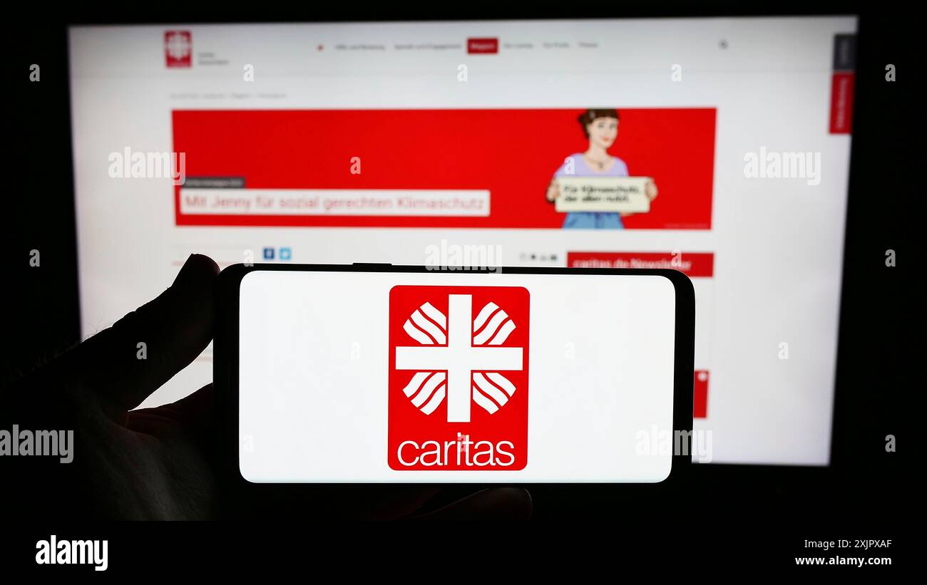 Stuttgart, Allemagne, 10-08-2023 : personne tenant un smartphone avec le logo de l'organisation allemande Deutscher Caritasverband e.V. devant le site. Mise au point Banque D'Images