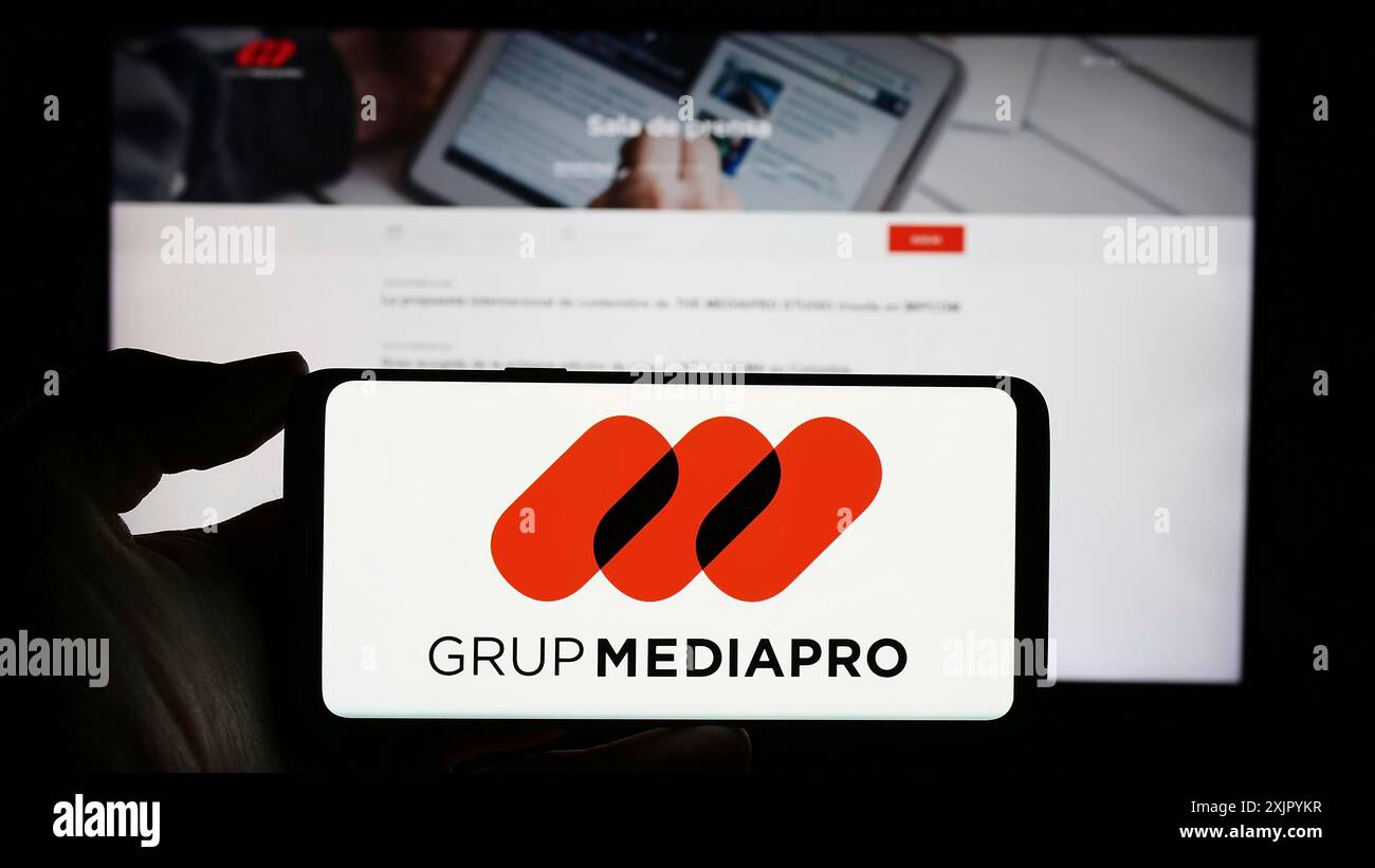 Stuttgart, Allemagne, 10-31-2023, personne tenant un téléphone portable avec le logo de la société multimédia espagnole Mediapro Group devant la page Web de l'entreprise. Mise au point Banque D'Images