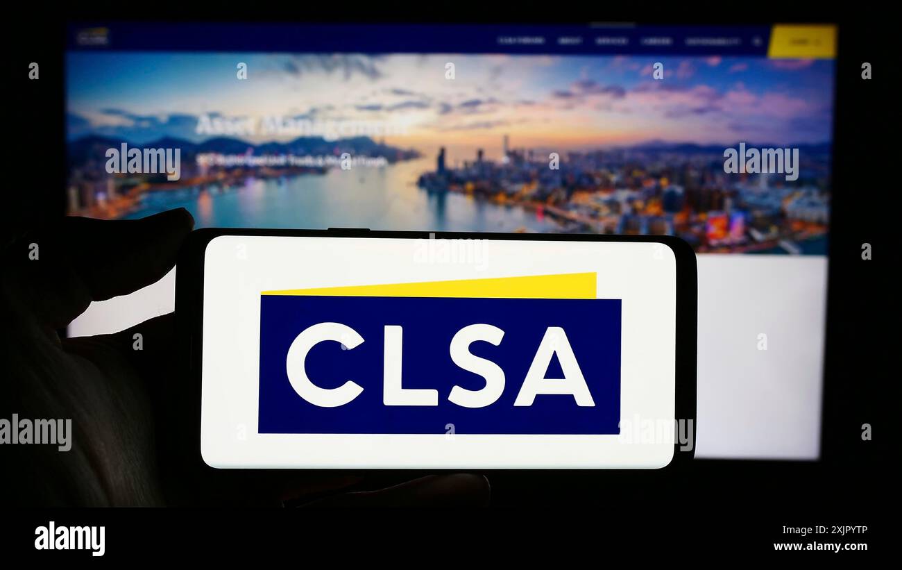 Stuttgart, Allemagne, 10 31 2023 : personne tenant un téléphone portable avec le logo de la société d'investissement de Hong Kong CLSA Ltd devant la page Web de l'entreprise. Mise au point Banque D'Images