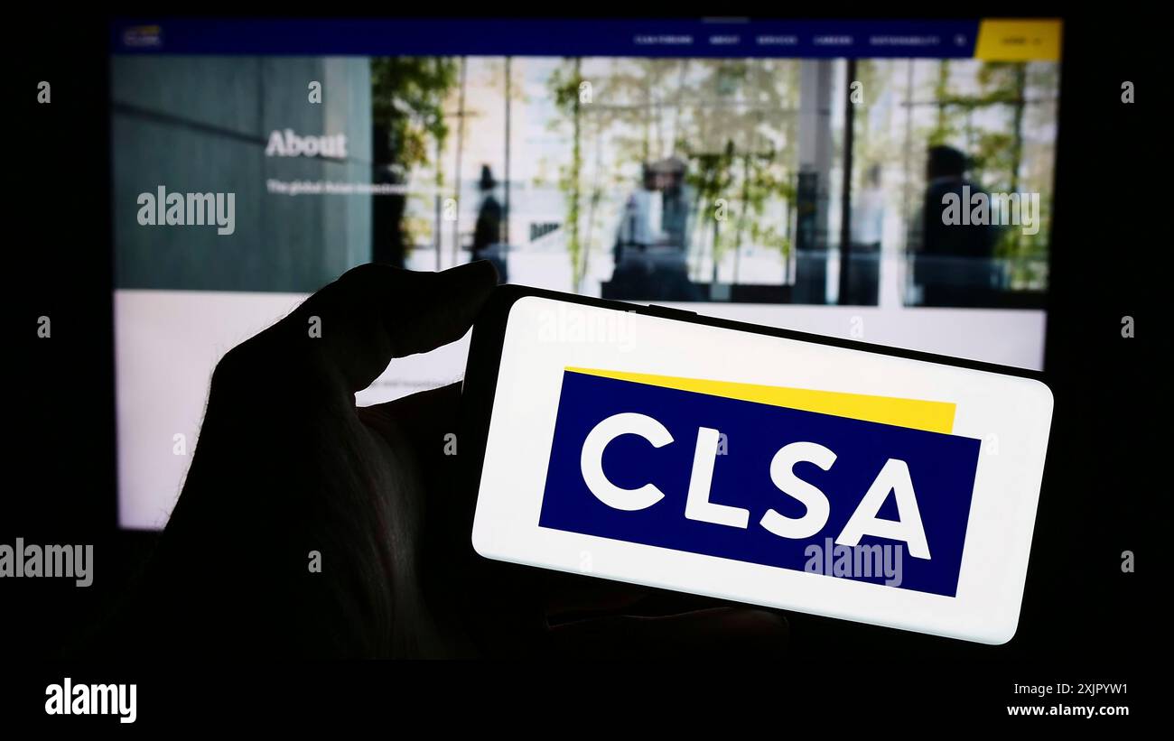 Stuttgart, Allemagne, 10 31 2023 : personne tenant un téléphone portable avec le logo de la société d'investissement de Hong Kong CLSA Ltd en face de la page Web de l'entreprise. Concentrez-vous sur Banque D'Images