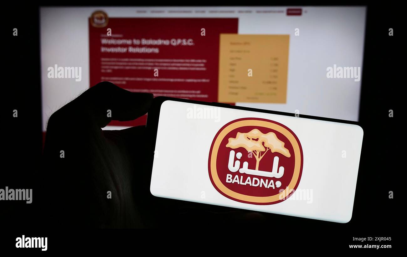 Stuttgart, Allemagne, 11-03-2023 : personne tenant un téléphone portable avec le logo de la société laitière et alimentaire qatari Baladna en face de la page Web de l'entreprise. Concentrez-vous sur Banque D'Images