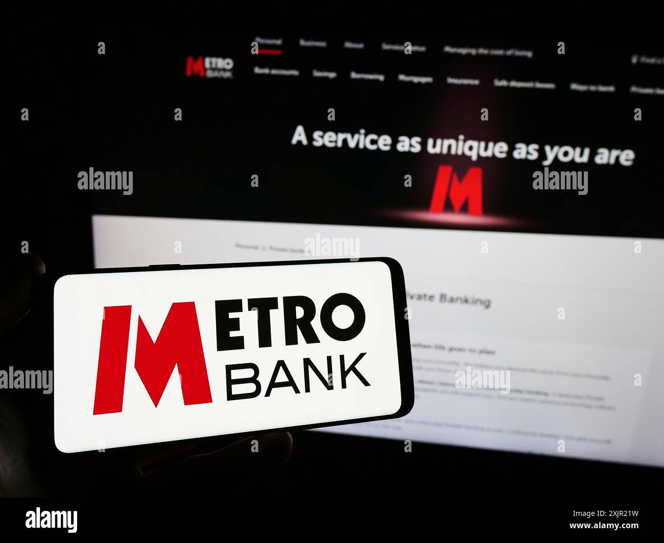 Stuttgart, Allemagne, 11-24-2023 : personne tenant un smartphone avec le logo de la société britannique de services financiers Metro Bank plc en face du site Web. Mise au point Banque D'Images