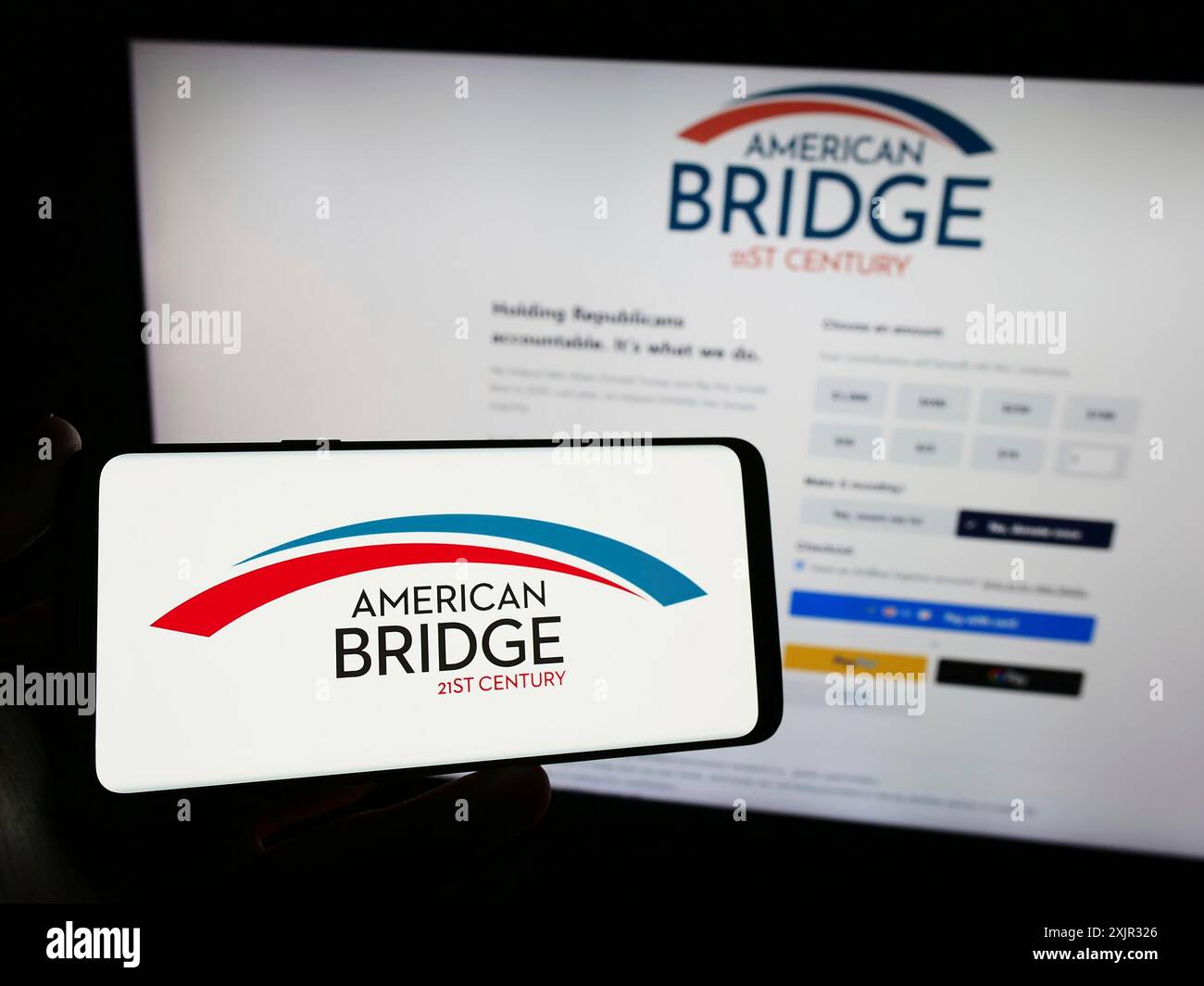 Stuttgart, Allemagne, 12-14-2023 : personne tenant un smartphone avec le logo du libéral Super PAC American Bridge 21st Century devant le site web. Concentrez-vous sur Banque D'Images