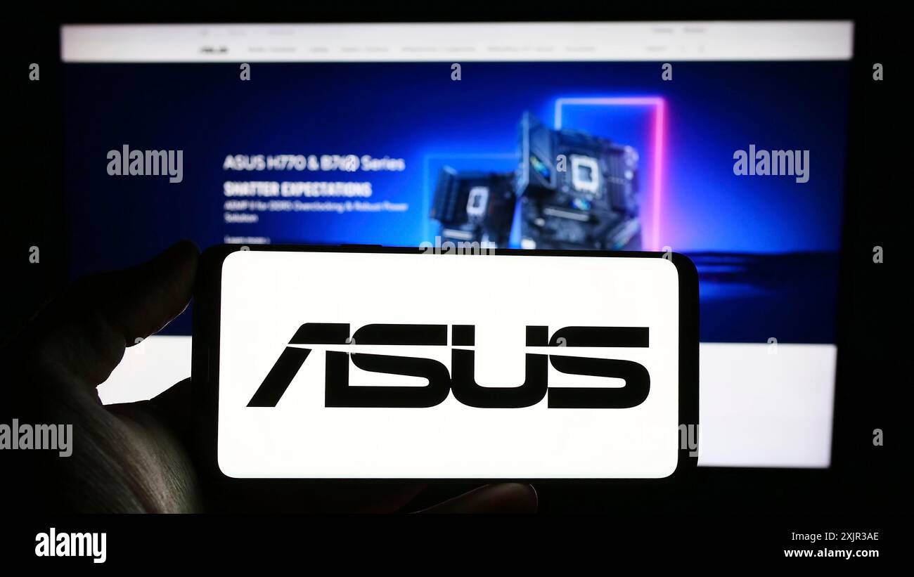 Stuttgart, Allemagne, 12-18-2023 : personne tenant un téléphone portable avec le logo de la société taïwanaise ASUSTeK Computer Inc (ASUS) en face de la page Web de l'entreprise. Banque D'Images
