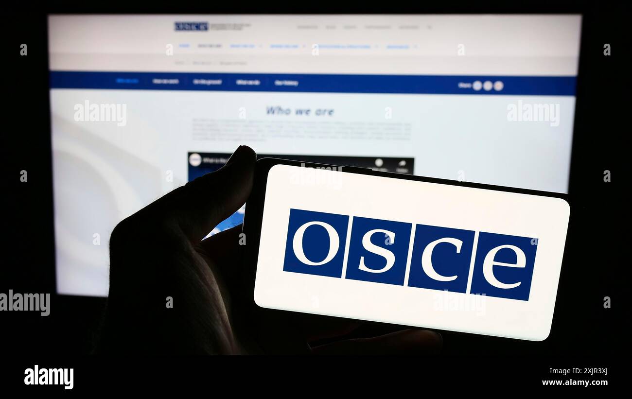 Stuttgart, Allemagne, 12-28-2023. Personne tenant un smartphone avec le logo de l'Organisation pour la sécurité et la coopération en Europe (OSCE) devant Banque D'Images