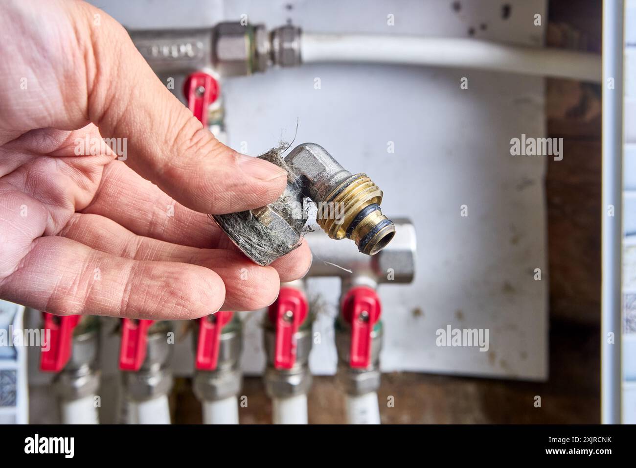 Raccord d'angle métallique pour tuyaux en plastique avec raccord à sertir et transition vers un filetage extérieur. Banque D'Images