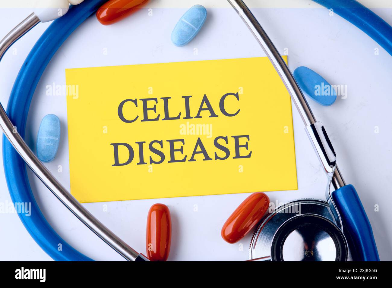 Concept de maladie cœliaque sans gluten. Mots MALADIE CŒLIAQUE sur une carte de visite jaune dans une composition avec un stéthoscope et des pilules Banque D'Images
