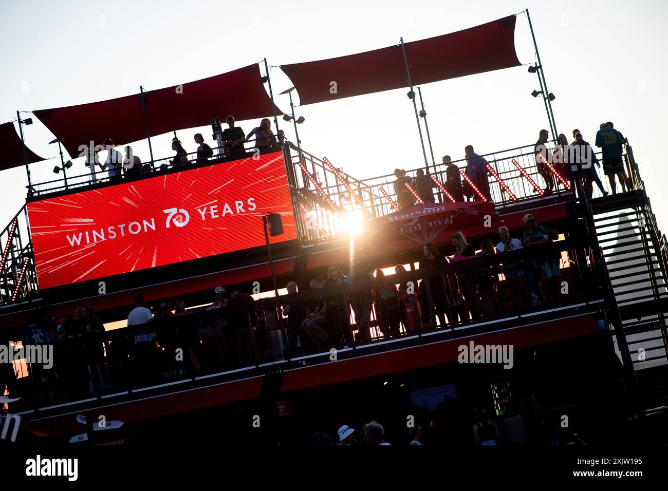 Nordholz, Allemagne. 18 juillet 2024. De nombreux festivaliers se tiennent sur une plateforme de la marque de cigarettes Winston devant le soleil couchant sur le site du Deichbrand Festival. Le festival en plein air avec environ 60 000 visiteurs a lieu du 18 au 21 juillet. Crédit : Hauke-Christian Dittrich/dpa/Alamy Live News Banque D'Images