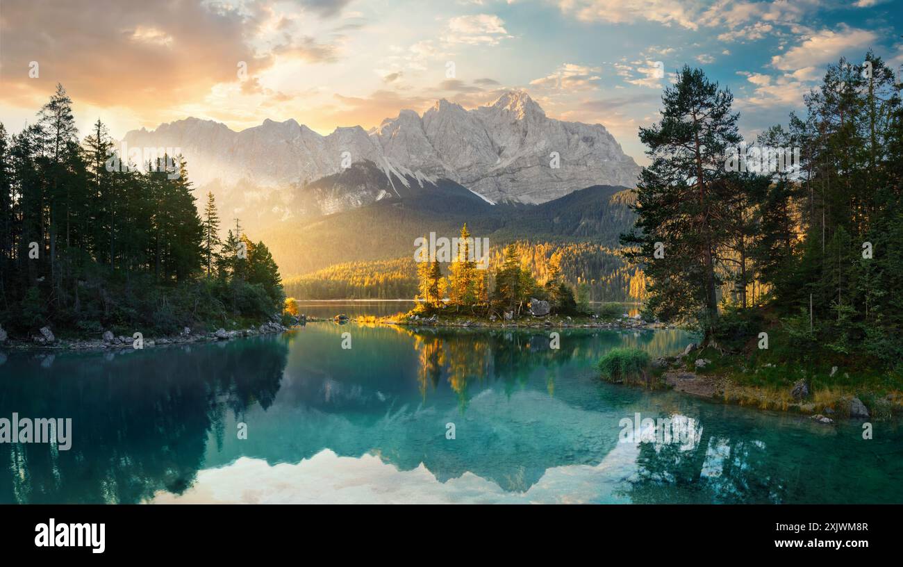 Paysage de lac peint en Allemagne avec des montagnes reflétées dans l'eau turquoise et un beau rayon de soleil du matin illuminant quelques arbres Banque D'Images
