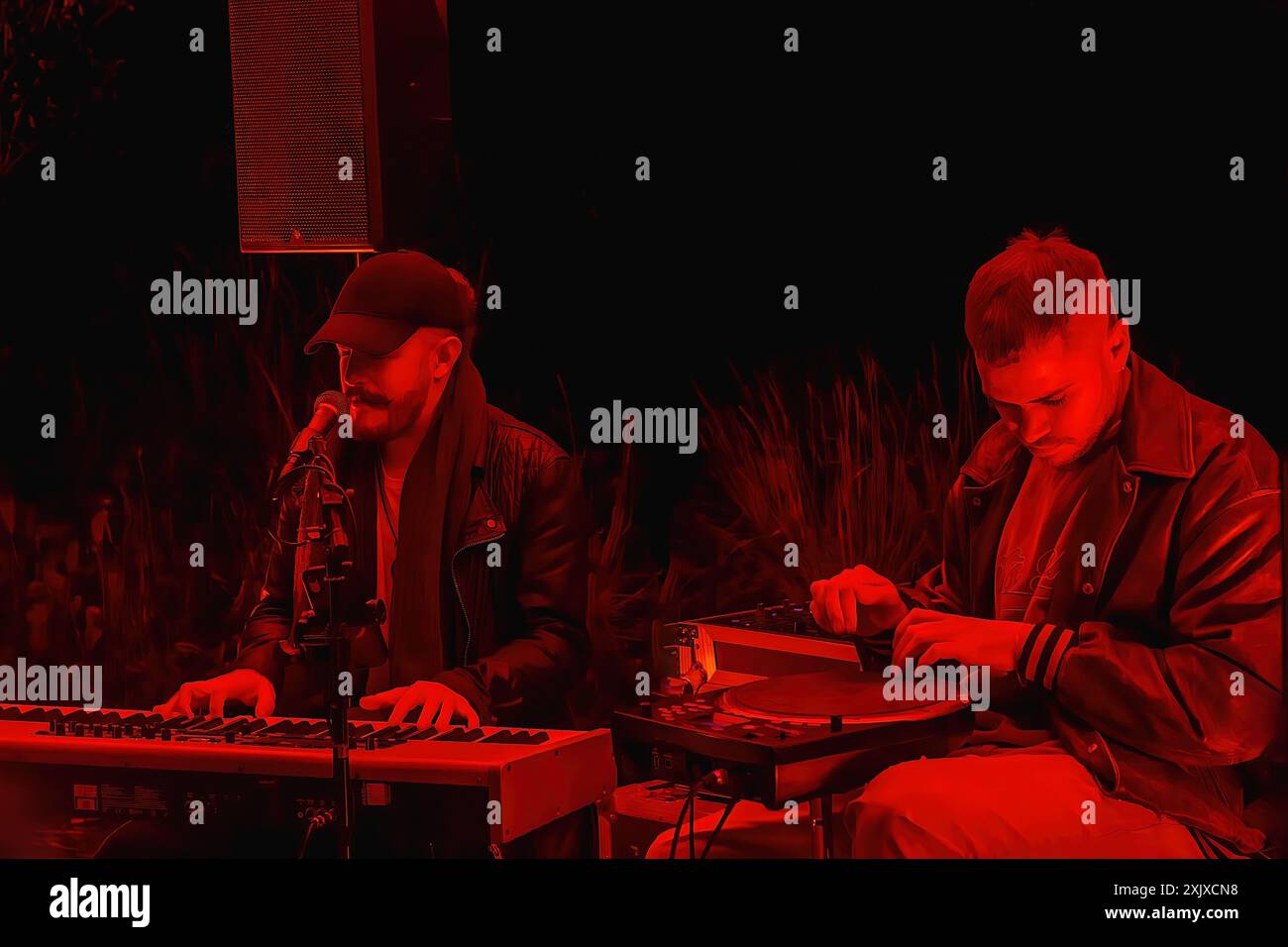 Deux musiciens se produisent en direct au festival Leeds Light Night, baigné de lumière rouge. Les éléments de platine et de clavier sont présentés, Leeds, West Yorkshire, Banque D'Images