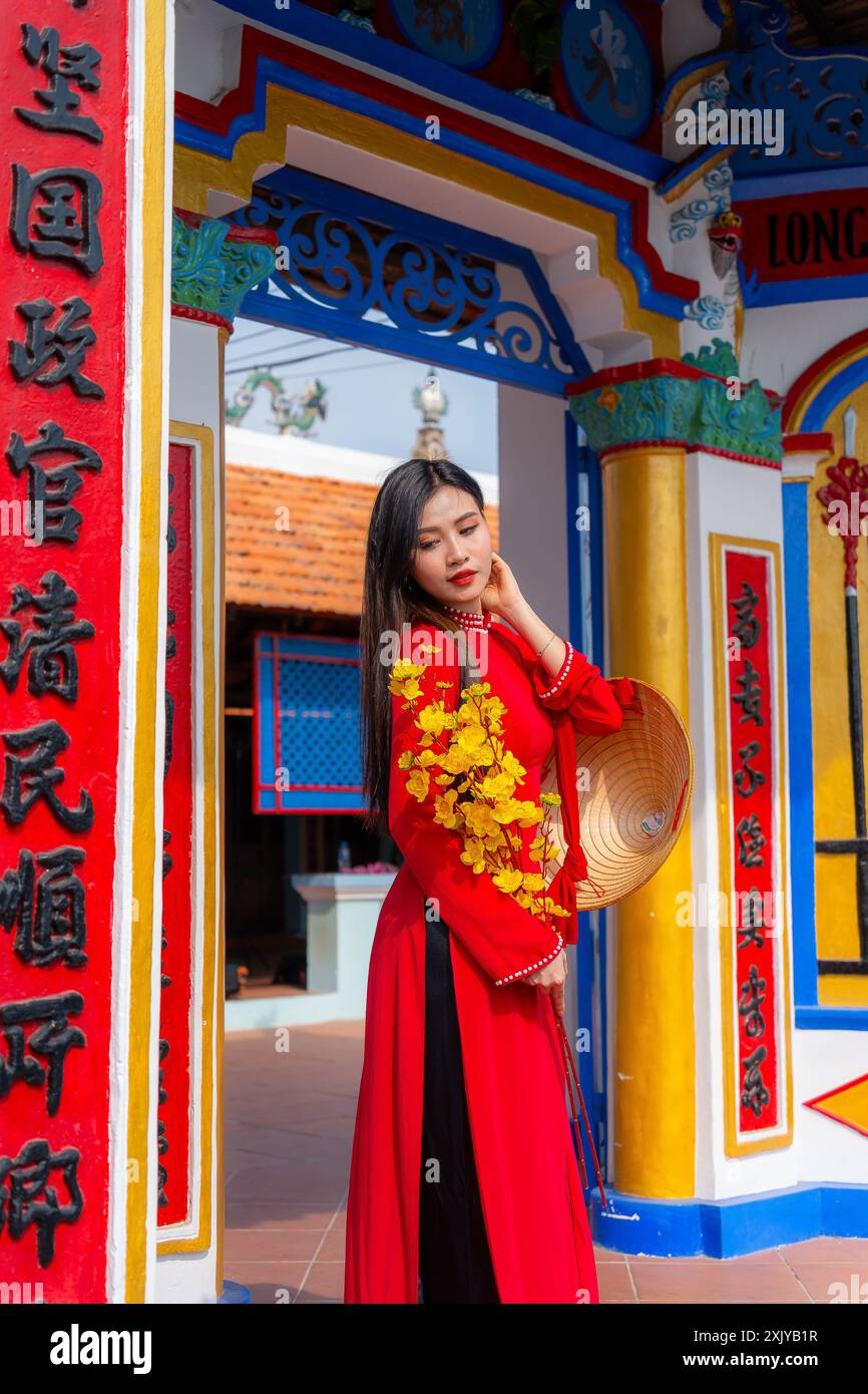 Fille vietnamienne avec la robe Ao Dai debout dans la maison traditionnelle du Vietnam. Texte en photo signifient meilleurs vœux à la famille, bonheur, prospérité, santé. T Banque D'Images