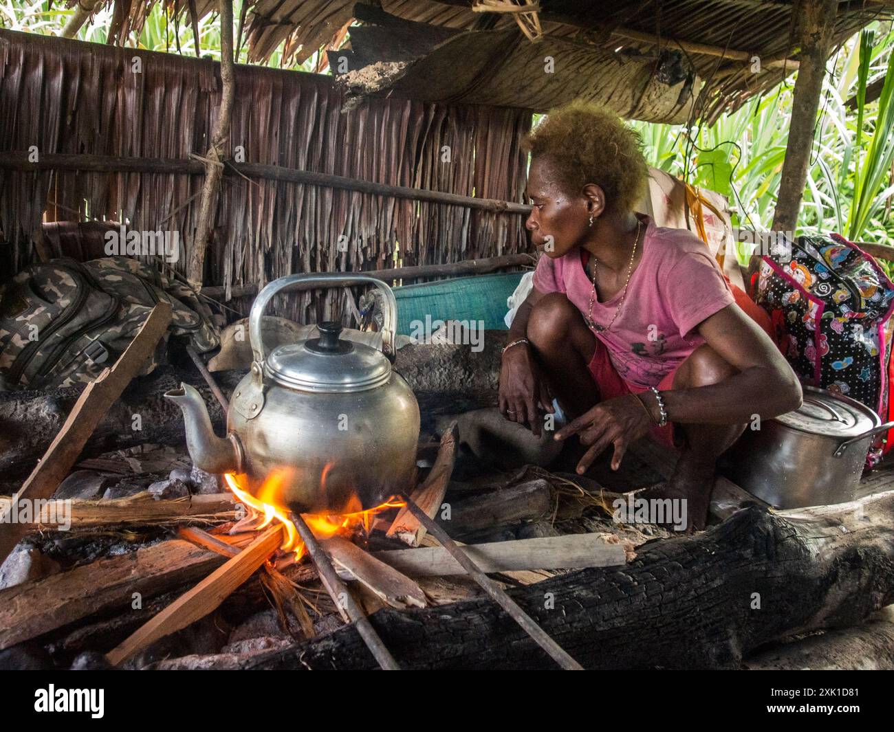 Jungle, Indonésie - le 13 janvier 2015 : femme de la tribu Korowai préparer les aliments sur la cheminée à l'intérieur de la maison en bois. La Papouasie occidentale, en Indonésie Banque D'Images