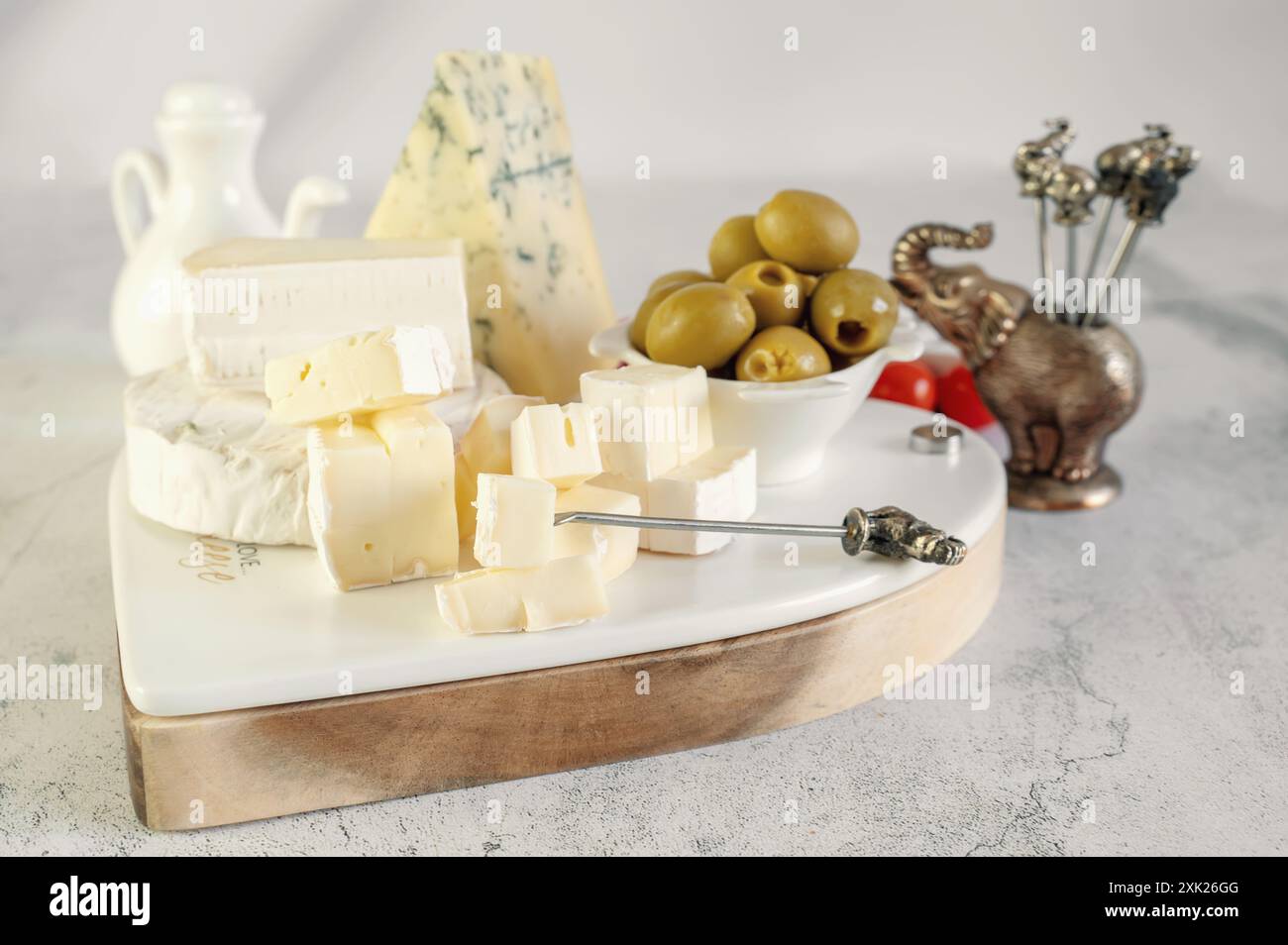 Délicieux fromages à moisissure blanche avec des olives sur un plateau de fromage original en forme de cœur. Un assortiment de fromages avec des moisissures blanches et bleues sur la table Banque D'Images