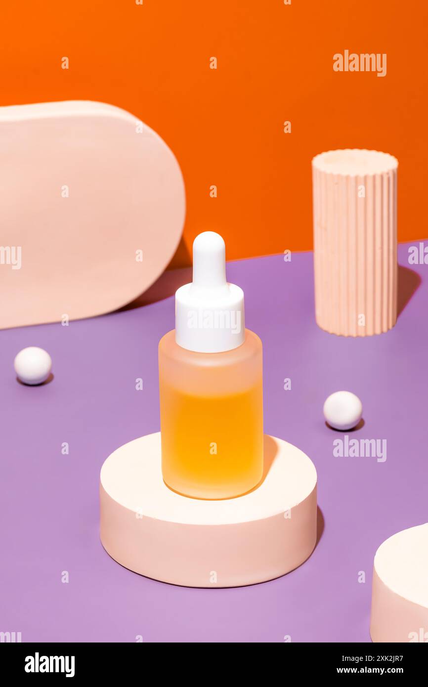 Un flacon compte-gouttes rempli de liquide orange prend place sur un podium circulaire blanc, sur un fond bicolore vibrant de violet et orange, accom Banque D'Images