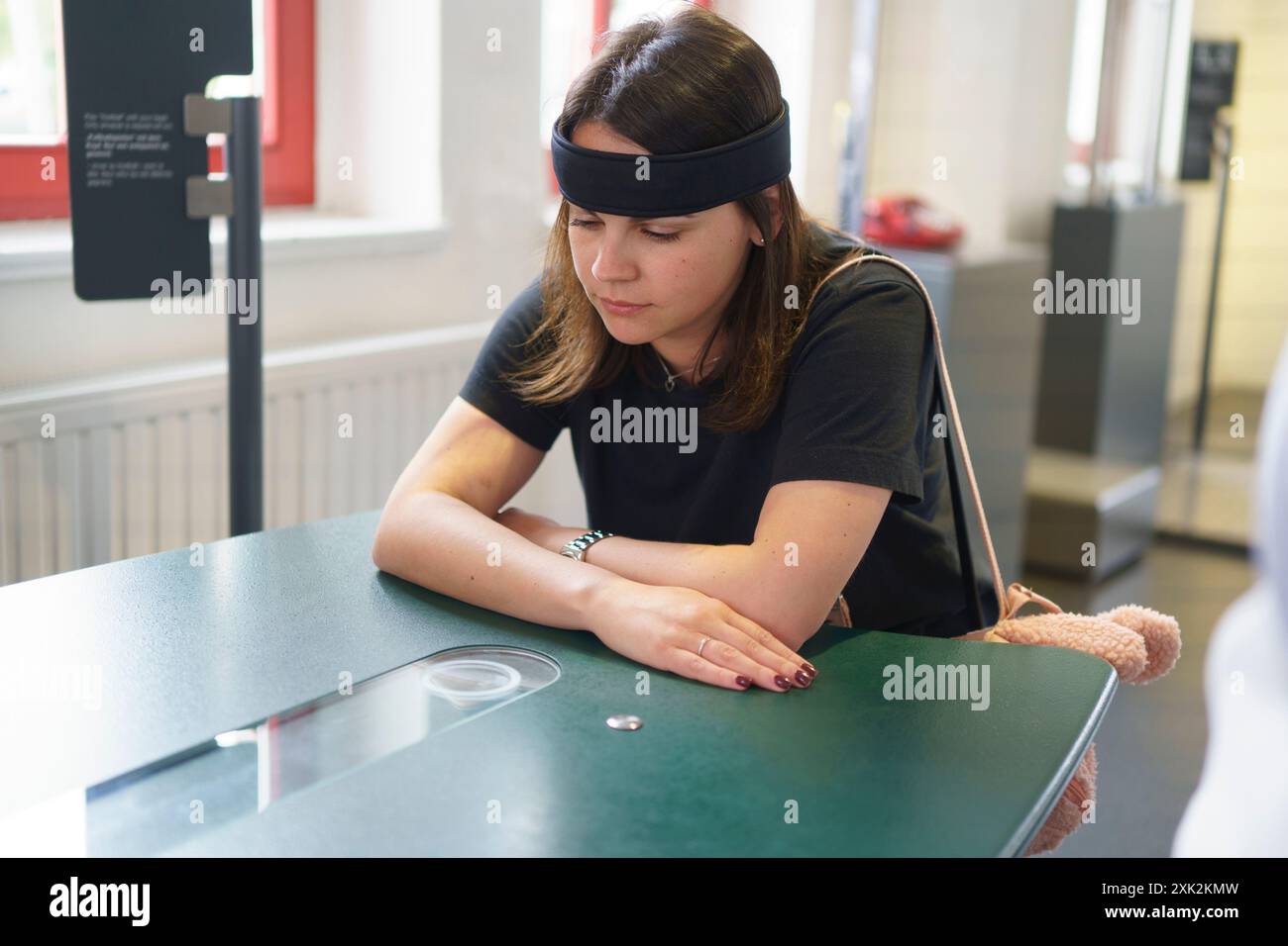 Une jeune femme est assise à une table avec un bandeau à capteur qui mesure l'activité cérébrale. Concept de science appliquée dans la vie réelle Banque D'Images